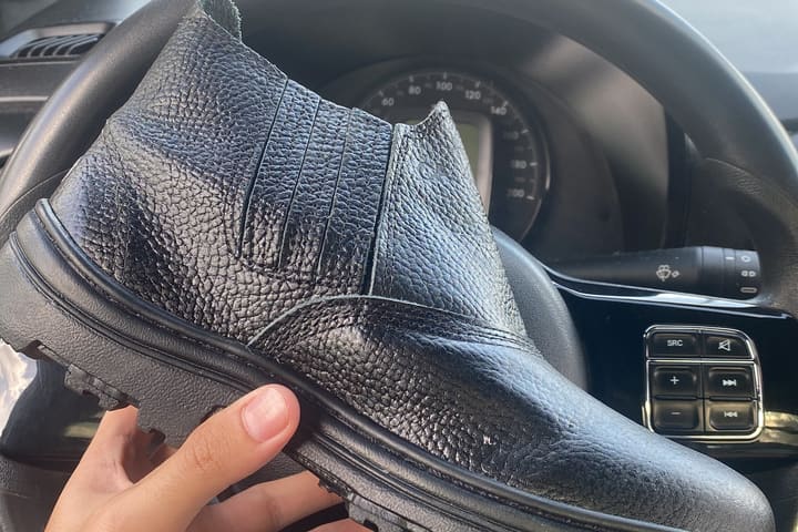 A black leather work boot from the range I sourced, held up in the car.