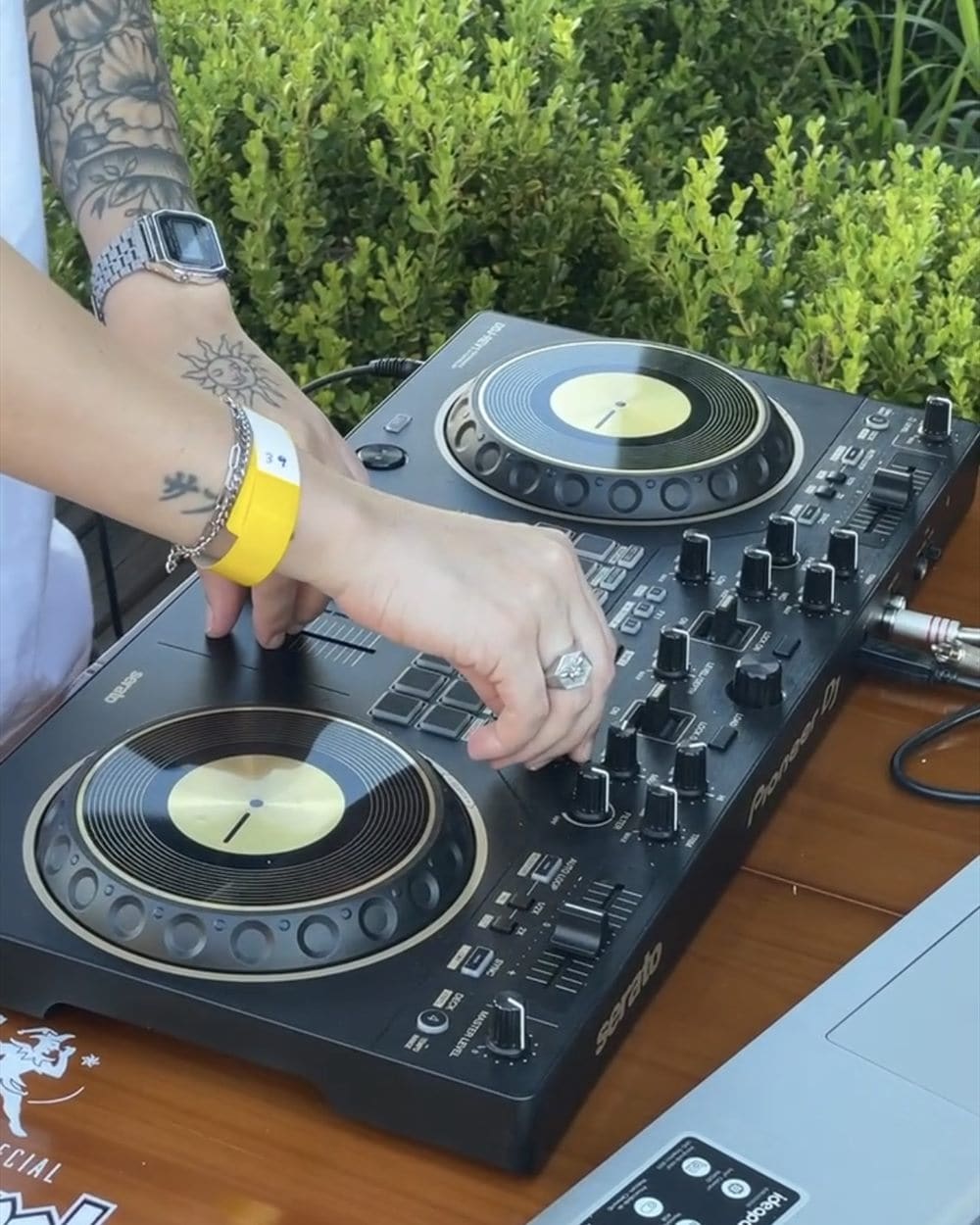 A DJ mixing on a controller set up on a table on the terrace of the bar and café.