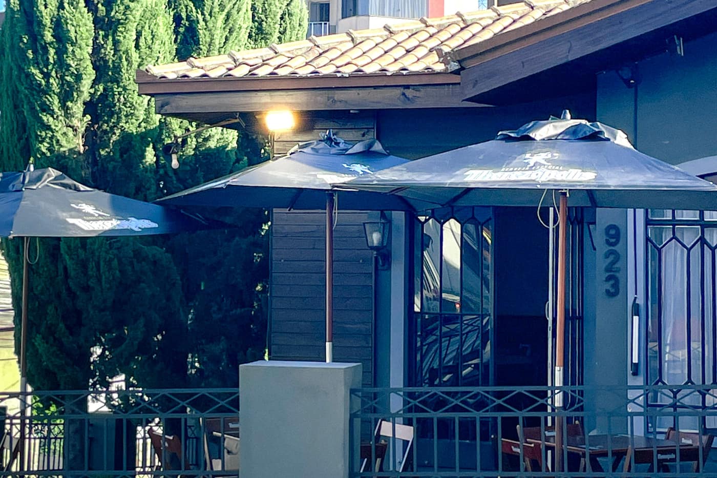 The street frontage of the bar and café: a tiled-roof house behind a low wall, with parasols over the terrace tables.